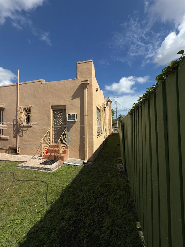 view of side of home featuring a yard, a patio, stucco siding, entry steps, and fence