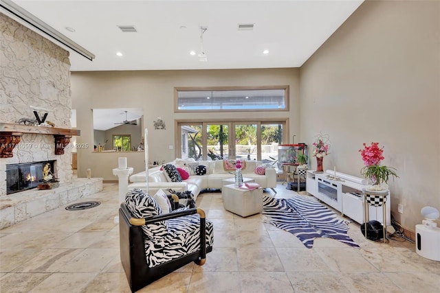 living room with a fireplace, a towering ceiling, and ceiling fan