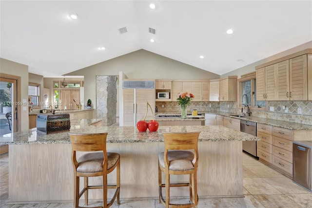 kitchen with dishwasher, light stone counters, a breakfast bar, and kitchen peninsula