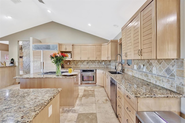 kitchen with a center island, appliances with stainless steel finishes, light stone countertops, and tasteful backsplash