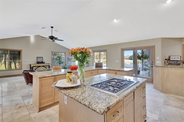 kitchen with light stone countertops, a kitchen island, light brown cabinetry, and stainless steel gas stovetop