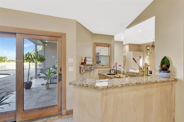 kitchen with sink, light stone counters, and kitchen peninsula