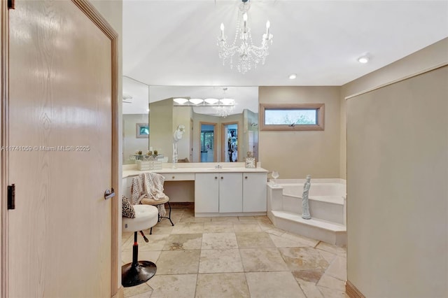 bathroom with a notable chandelier, vanity, and a bath