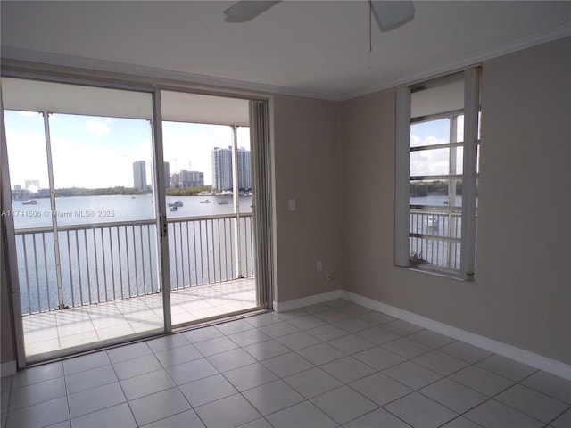 tiled empty room with a water view, ceiling fan, crown molding, and a wealth of natural light