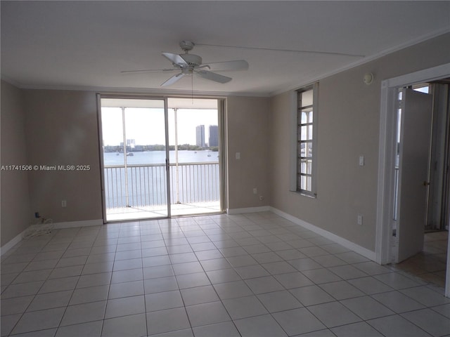 tiled empty room with a water view, ceiling fan, ornamental molding, and expansive windows