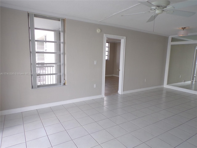 spare room with light tile patterned floors, ornamental molding, and ceiling fan