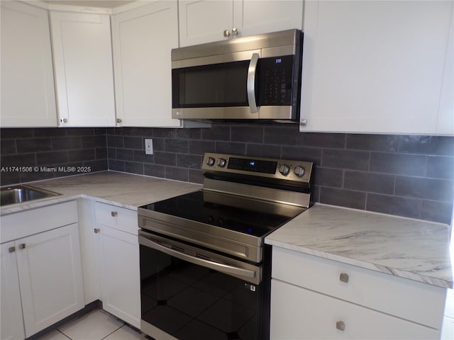 kitchen featuring white cabinetry, appliances with stainless steel finishes, light stone countertops, and backsplash