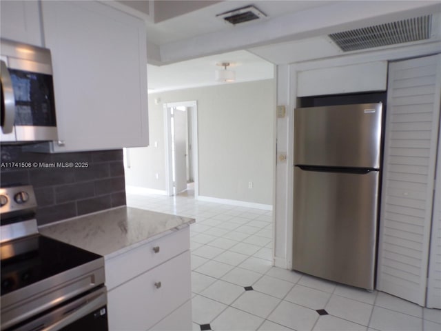 kitchen with white cabinetry, stainless steel appliances, light stone counters, tasteful backsplash, and light tile patterned flooring