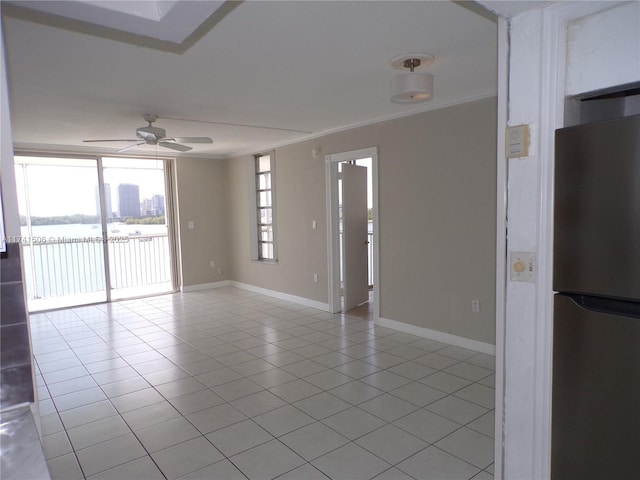 tiled empty room with a water view, ceiling fan, and ornamental molding