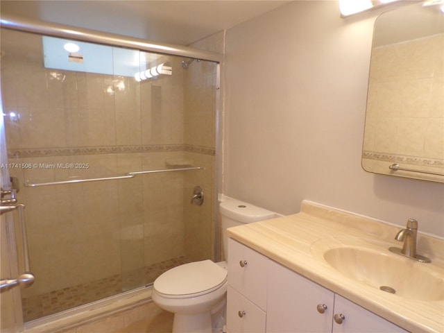 bathroom featuring vanity, a shower with shower door, and toilet