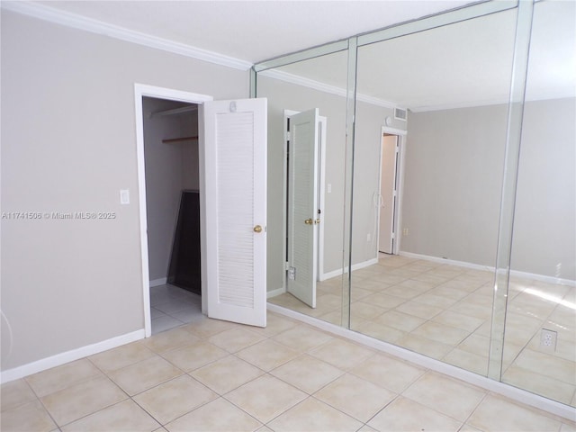 unfurnished bedroom with light tile patterned floors, crown molding, and a closet