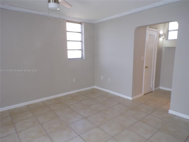 tiled empty room featuring ceiling fan and ornamental molding