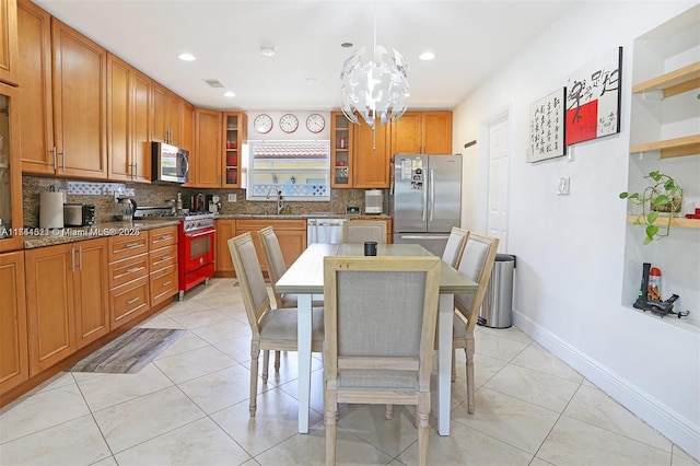 kitchen with light stone countertops, decorative light fixtures, appliances with stainless steel finishes, brown cabinets, and glass insert cabinets