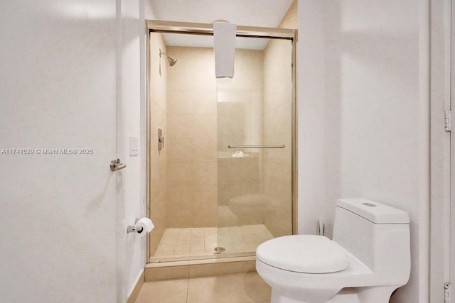 bathroom featuring tile patterned floors, toilet, and walk in shower