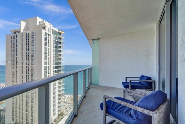 balcony with a water view and a view of the beach