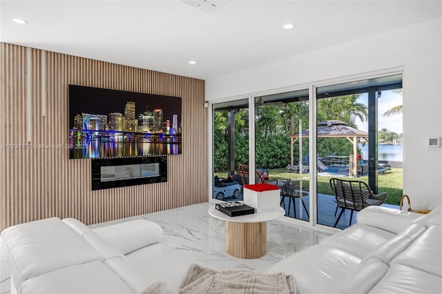 living area with recessed lighting, marble finish floor, and a water view