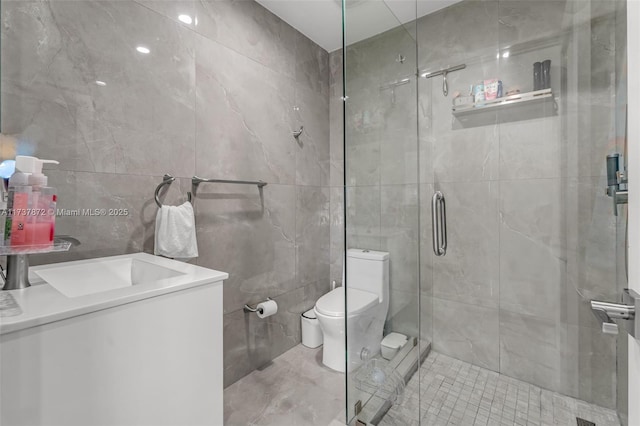 bathroom featuring toilet, vanity, a shower stall, and tile walls