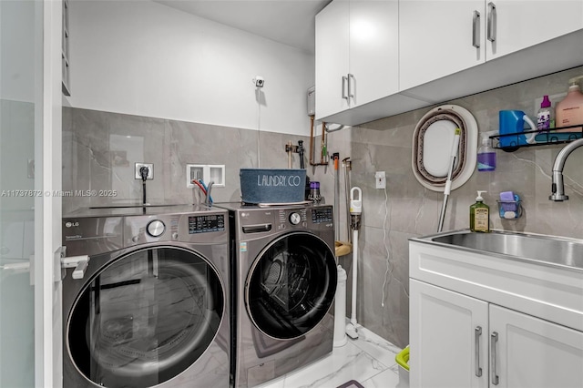 laundry area with washing machine and dryer, a sink, tile walls, marble finish floor, and cabinet space