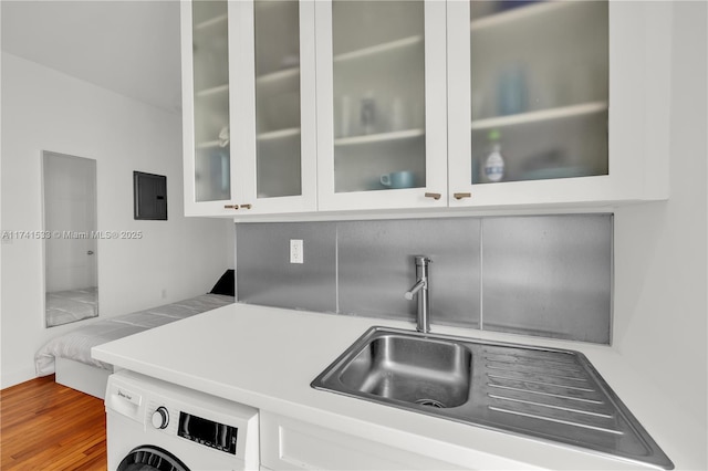 kitchen with hardwood / wood-style flooring, white cabinetry, washer / dryer, and electric panel