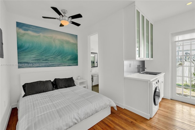 bedroom featuring washer / clothes dryer, hardwood / wood-style flooring, sink, and ensuite bath