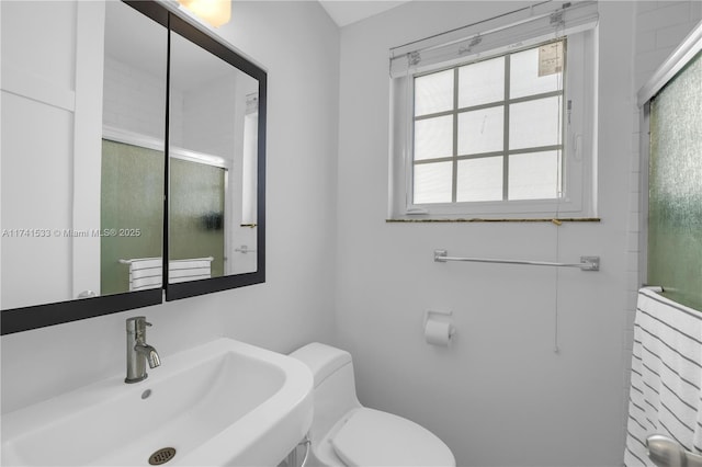 bathroom featuring sink, an enclosed shower, and toilet