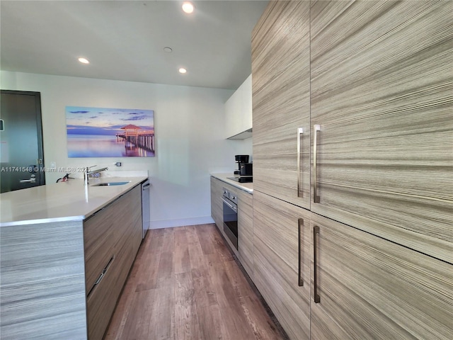 kitchen featuring appliances with stainless steel finishes, pendant lighting, wood-type flooring, sink, and kitchen peninsula