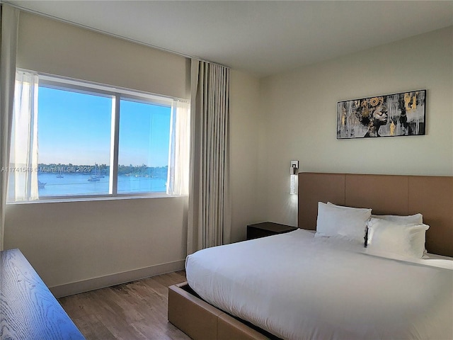 bedroom featuring light hardwood / wood-style floors and a water view