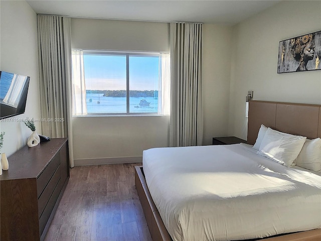 bedroom featuring wood-type flooring and a water view