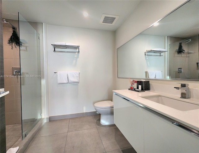 bathroom featuring tile patterned flooring, vanity, toilet, and tiled shower