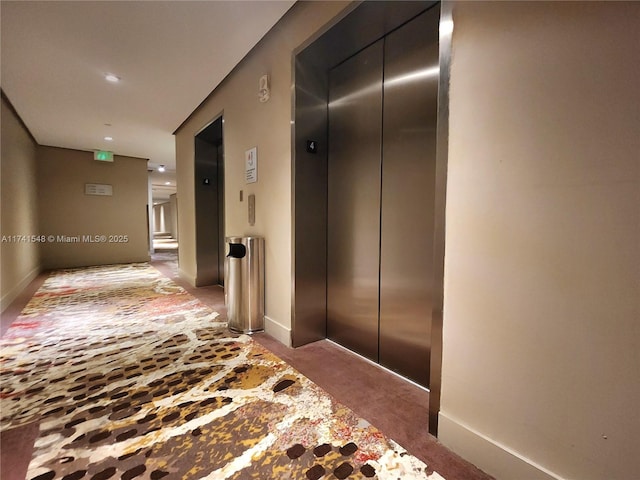 hallway featuring elevator and carpet