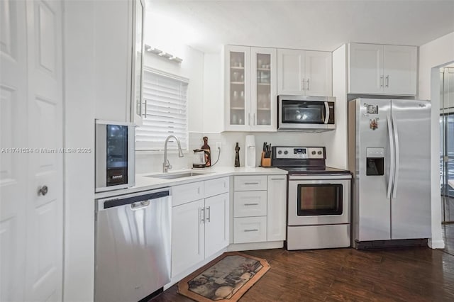 kitchen with dark wood-style floors, stainless steel appliances, glass insert cabinets, white cabinets, and a sink