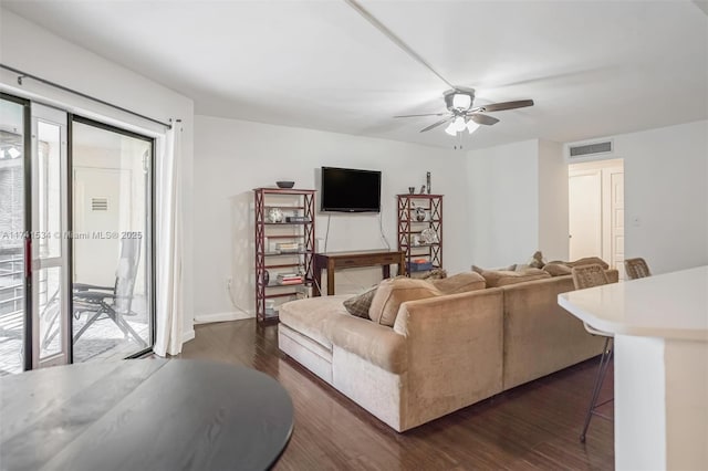 living room featuring a healthy amount of sunlight, a ceiling fan, visible vents, and dark wood-type flooring