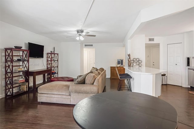 living room with dark wood-style flooring, visible vents, and a ceiling fan