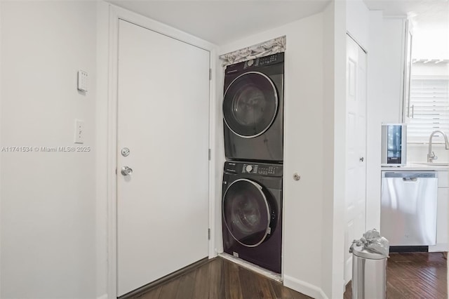 laundry room featuring laundry area, dark wood-type flooring, a sink, and stacked washer / drying machine