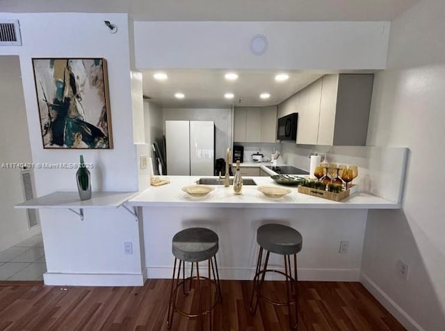 kitchen featuring white fridge, sink, a kitchen bar, and kitchen peninsula