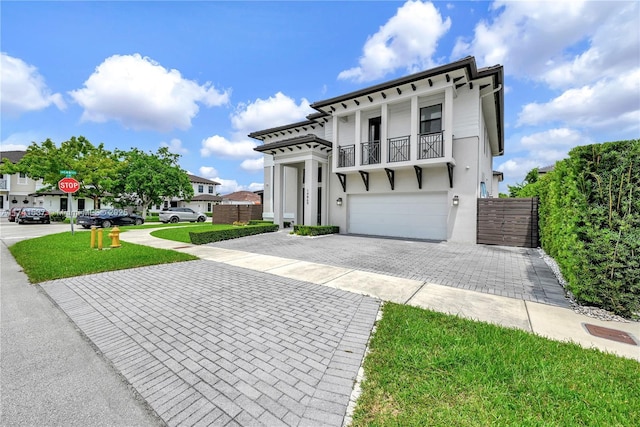 view of front of house with a balcony, a garage, and a front lawn