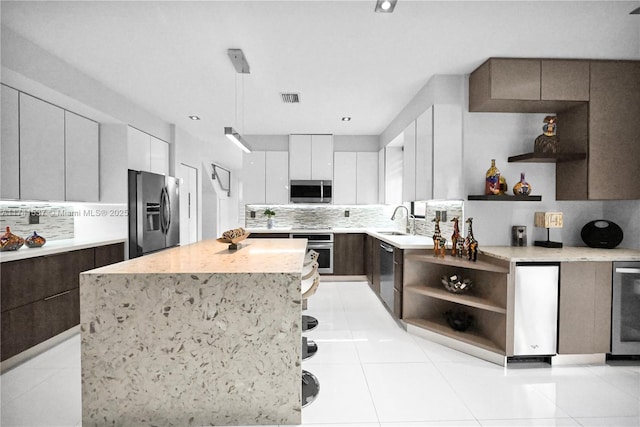 kitchen with sink, white cabinetry, a kitchen island, stainless steel appliances, and backsplash