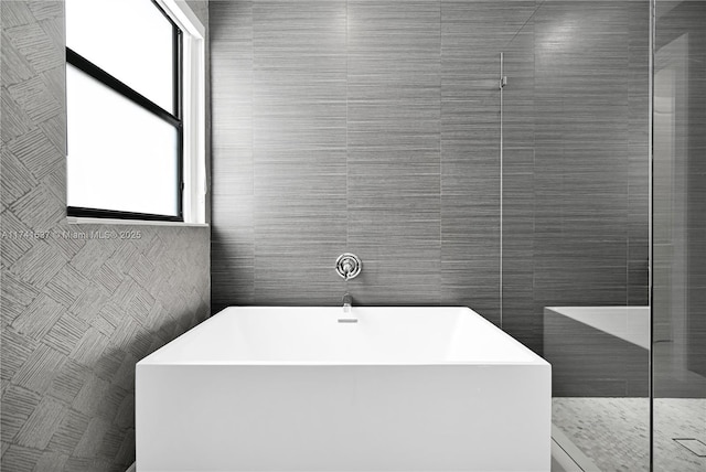 bathroom featuring independent shower and bath and tile walls