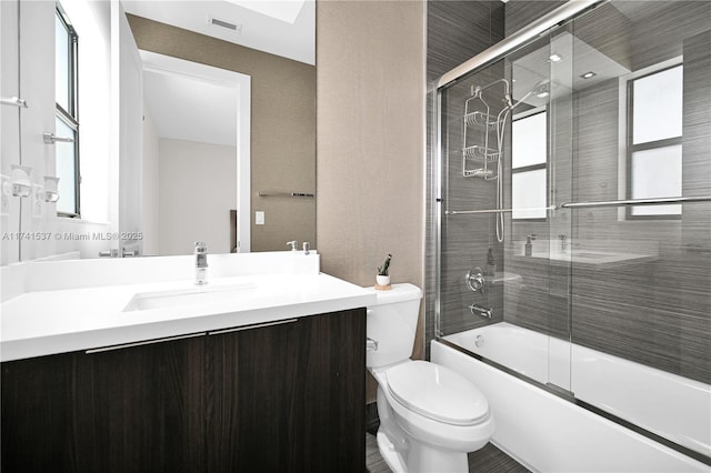 full bathroom featuring vanity, toilet, and combined bath / shower with glass door