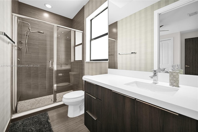 bathroom featuring vanity, a shower with shower door, and toilet