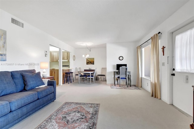 carpeted living room with an inviting chandelier