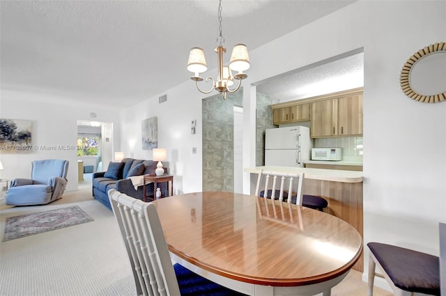 dining space featuring an inviting chandelier, light colored carpet, and a textured ceiling