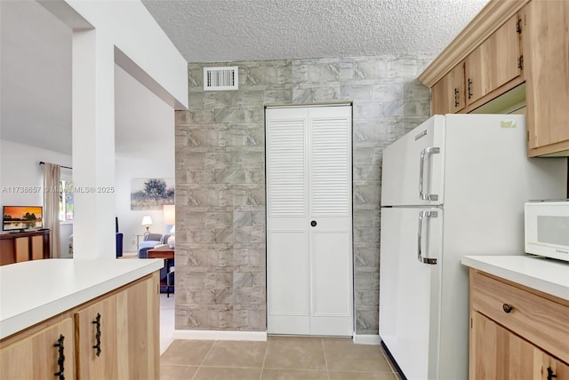 kitchen with light brown cabinets, light tile patterned floors, white appliances, and tile walls