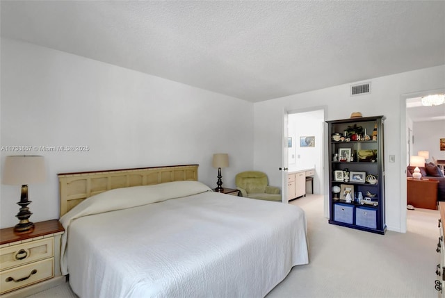 carpeted bedroom featuring ensuite bath and a textured ceiling