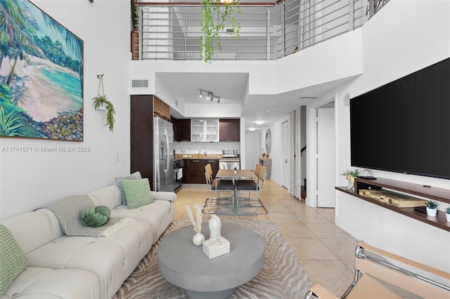 living room featuring a high ceiling, rail lighting, and light tile patterned floors