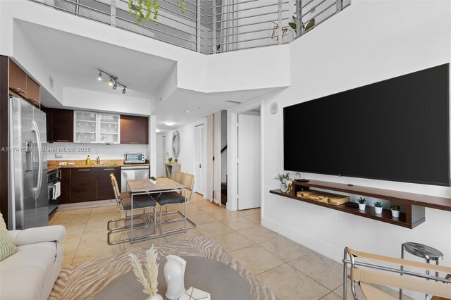 tiled living room featuring a high ceiling and track lighting