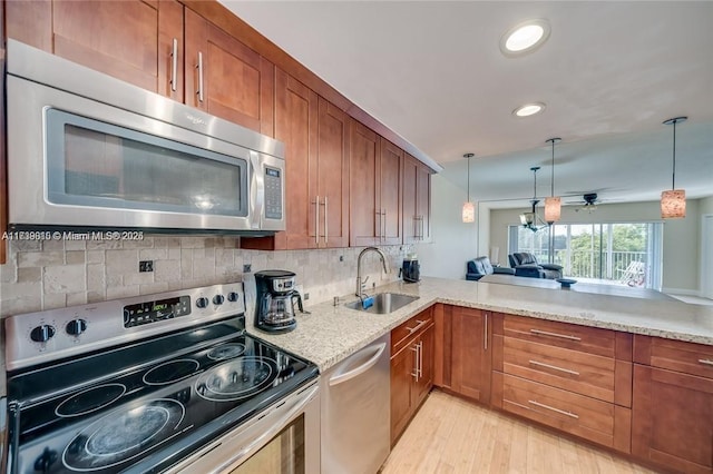 kitchen with sink, decorative light fixtures, kitchen peninsula, stainless steel appliances, and backsplash