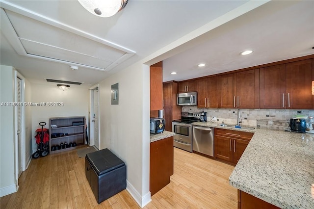 kitchen featuring sink, backsplash, light stone counters, light hardwood / wood-style floors, and stainless steel appliances