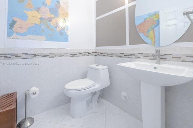 bathroom featuring toilet, tile patterned flooring, and tile walls