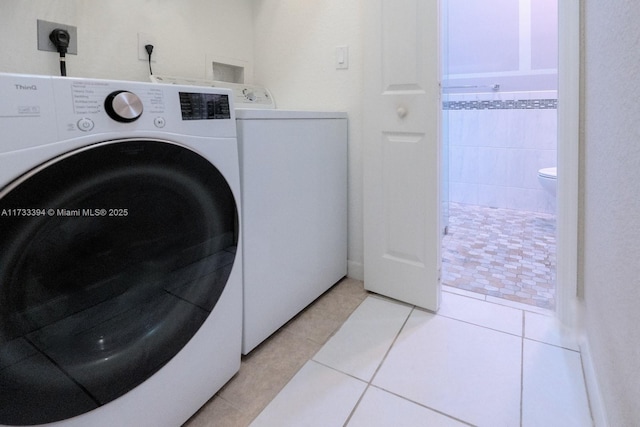 washroom with separate washer and dryer and light tile patterned floors